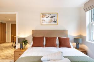 1 dormitorio con 1 cama blanca grande con almohadas marrones en Rock Mill Apartment 12, en Stony Middleton