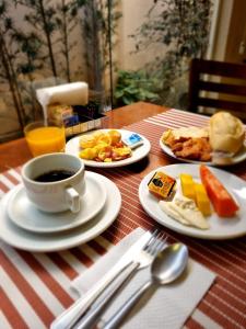a table with plates of food and a cup of coffee at Grande Hotel Itaguaí in Itaguaí