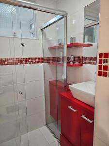 a bathroom with a sink and a glass shower at Apartamentos na Praia do Gonzaga in Santos