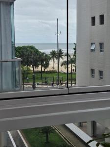 een uitzicht op het strand vanuit een raam van een gebouw bij Apartamentos na Praia do Gonzaga in Santos