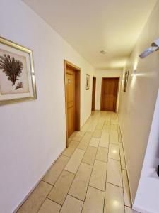 a hallway with white walls and a tile floor at Hotel Kanta in Kappel-Grafenhausen +6 photos