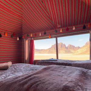 two beds in a room with a view of the desert at Star Walk Camp & Tours in Wadi Rum