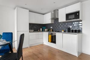 Livestay-Modern Apartments Building in Aylesbury في Buckinghamshire: مطبخ مع دواليب بيضاء وطاولة طعام