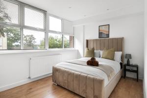 una camera da letto con un grande letto con un orso bruno sopra di Livestay-Modern Apartments Building in Aylesbury a Buckinghamshire