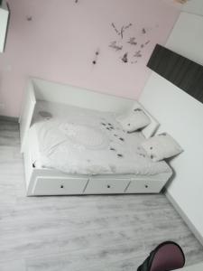 Una cama blanca en una habitación blanca con un cajón en Location 24H Le Mans, en Marigné-Laillé
