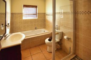 a bathroom with a tub and a toilet and a sink at Dalene se Seehuis, Langebaan, 8-sleeper in Langebaan +17 photos