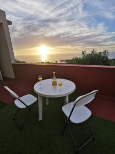 uma mesa e duas cadeiras numa varanda com o pôr-do-sol em Casa Las Tías Tazacorte em Tazacorte