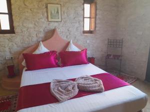 ein Schlafzimmer mit einem großen Bett mit rosa Kissen in der Unterkunft Riad Mamy Wababi in Essaouira