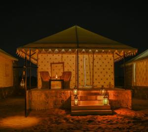 The Carvaans Resort في جيلسامر: خيمة بها كرسيين وطاولة بها إضاءة