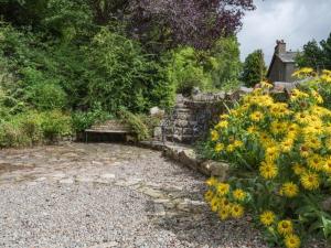 a bench in a garden with yellow flowers at 3 Bed in Eskdale SZ416 in Santon Bridge