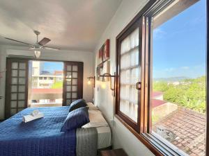 um quarto com uma cama azul e uma grande janela em Pousada Canajurê em Florianópolis