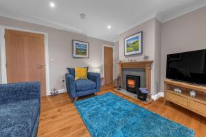 a living room with a television and a fireplace at Summerbank Cottage, luxury Lake District holiday home in Coniston in Coniston