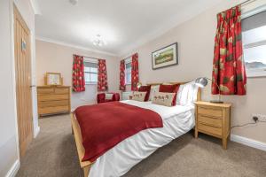 a bedroom with a large bed with red curtains at Summerbank Cottage, luxury Lake District holiday home in Coniston in Coniston
