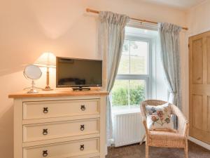 a bedroom with a dresser with a television and a chair at 3 bed in Ullock SZ043 in Arlecdon