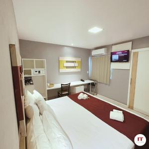 a hotel room with a large bed and a desk at Grande Hotel Itaguaí in Itaguaí