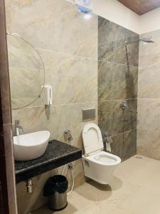 een badkamer met een wastafel, een toilet en een spiegel bij The Deerfield Cottages in Rāmnagar