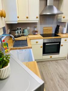 uma cozinha com armários brancos e um forno com placa de fogão em Caerau Heights em Newport