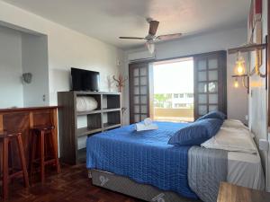 a bedroom with a bed with a blue blanket and a window at Pousada Canajurê in Florianópolis