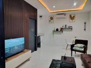 un soggiorno con TV e divano di B.leaf villa บีลีฟ วิลล่า a Petchaburi