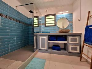 niebieska łazienka z umywalką i lustrem w obiekcie PEACE & LODGE II w mieście Saint-Joseph