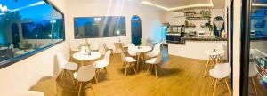 un restaurante con mesas y sillas blancas en una habitación en B.leaf villa บีลีฟ วิลล่า, en Cha Am