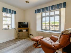 a living room with a couch and a tv and two windows at 2 Bed in Tenby 87912 in Tenby
