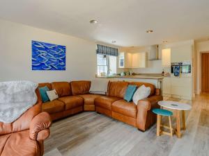 a living room with a brown couch and a kitchen at 2 Bed in Tenby 87912 in Tenby