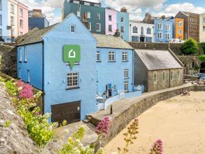 a blue house on the beach with buildings in the background at 2 Bed in Tenby 87912 in Tenby