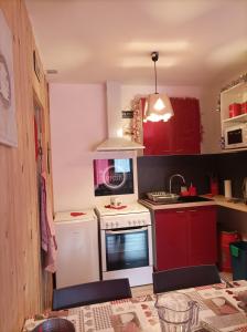 eine Küche mit roten Schränken und einem weißen Herd mit Backofen in der Unterkunft Gîte - Appartement - sans draps et serviettes in Artigues