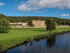 a large building in a field next to a river at 3 Bed in Matlock 86048 in Matlock