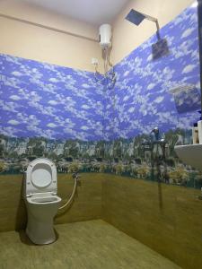 a bathroom with a toilet and a painting on the wall at Keylo Homes in Arambol