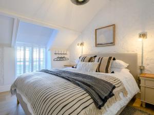 a bedroom with a large bed with a striped blanket at 3 Bed in Ogmore-by-Sea 86494 in Southerndown