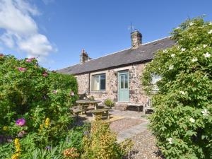 a stone cottage with a picnic table in the garden at 4 bed in Mindrum 86272 