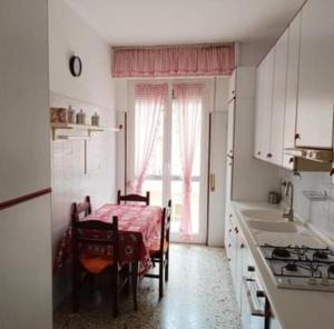 a white kitchen with a table and a kitchen with a window at Appartamento LOANO in Loano
