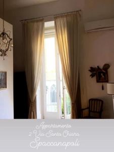 Cette chambre dispose d'une grande fenêtre avec des rideaux. dans l'établissement MARIA ROSARIA A SANTA CHIARA, à Naples