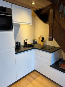 une cuisine avec des armoires blanches et un comptoir noir dans l'établissement CHALET LE REPAIRE PROCHE PISTE, à Megève 9 autres photos