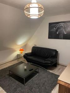 a living room with a black leather couch and a table at 3 Room City Apartment 90m2 in Heilbronn