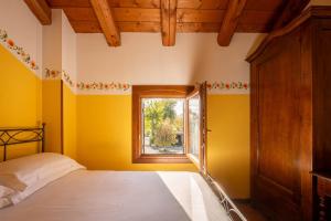 a bedroom with yellow walls and a bed with a window at Locanda al Convento in Favaro Veneto