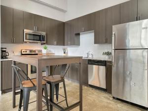 a kitchen with a table and a stainless steel refrigerator at Stunning Downtown Studio With Rooftop Patio in Des Moines