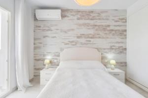 a white bedroom with a bed and two night stands at Espanatour MENORCA in Dehesa de Campoamor