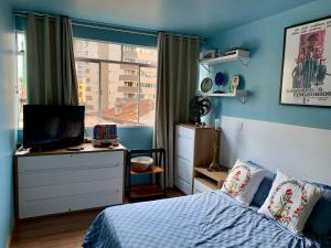 um quarto com uma cama e uma secretária com uma televisão em Apartamento Teatro Conforto no Centro em Curitiba