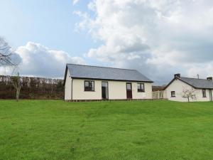 a white house with a large grassy yard at Country Cottage in Brecon