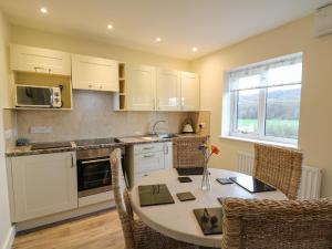 a kitchen with a table and chairs and a kitchen with white cabinets at Country Cottage in Brecon