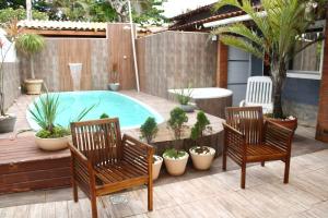 a patio with two chairs and a swimming pool at Pousada Recanto Beach House - Cabo Frio - Unamar in Tamoios