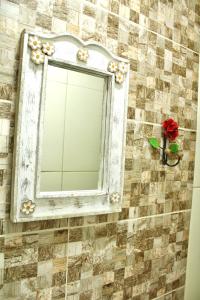 a mirror on a tiled wall with a red rose at Pousada Recanto Beach House - Cabo Frio - Unamar in Tamoios