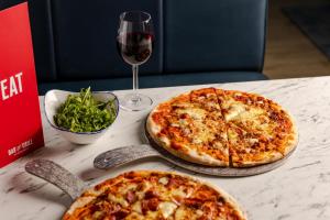two pizzas sitting on a table with a glass of wine at Leonardo Inn Aberdeen Airport in Dyce