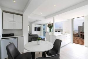 una cucina e un soggiorno con tavolo e sedie bianchi di Modern & Luxurious Seaside Apartment a Città del Capo