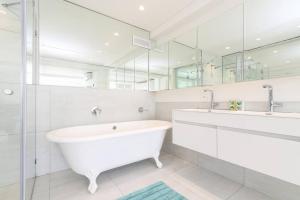 a white bathroom with a tub and a large mirror at Modern & Luxurious Seaside Apartment in Cape Town +26 photos
