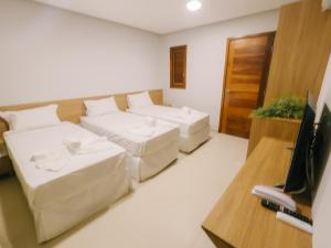 uma sala de estar com duas camas e uma televisão em Oiti Beach Resort Tutoia em Tutóia