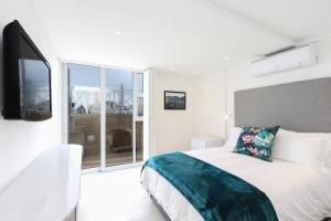 a white bedroom with a bed and a large window at Modern & Luxurious Seaside Apartment in Cape Town